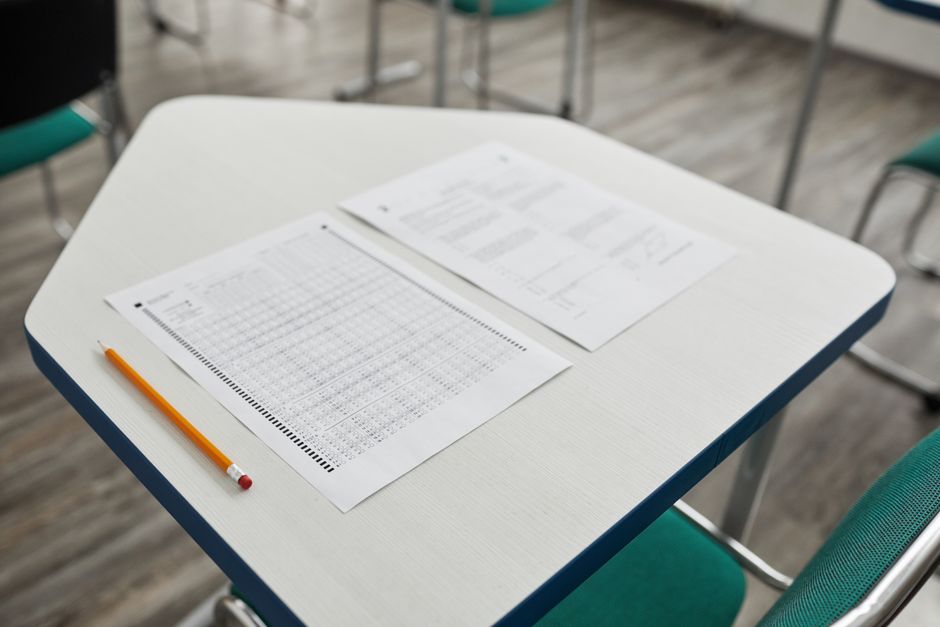 A close-up image of an exam paper and pencil on a classroom desk, ready for a test.
